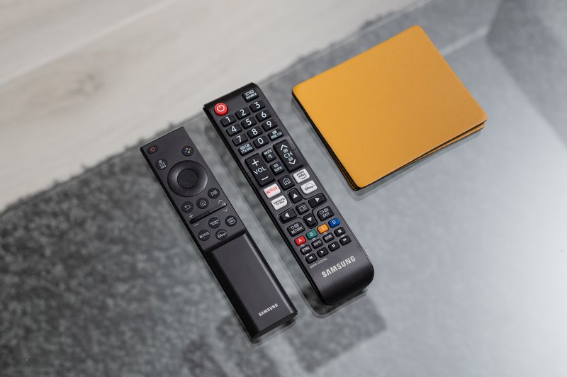 Two black remote controls and yellow notebook on light surface