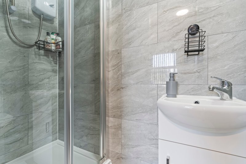 Modern bathroom with walk-in shower, marble tiles, white sink and mirror