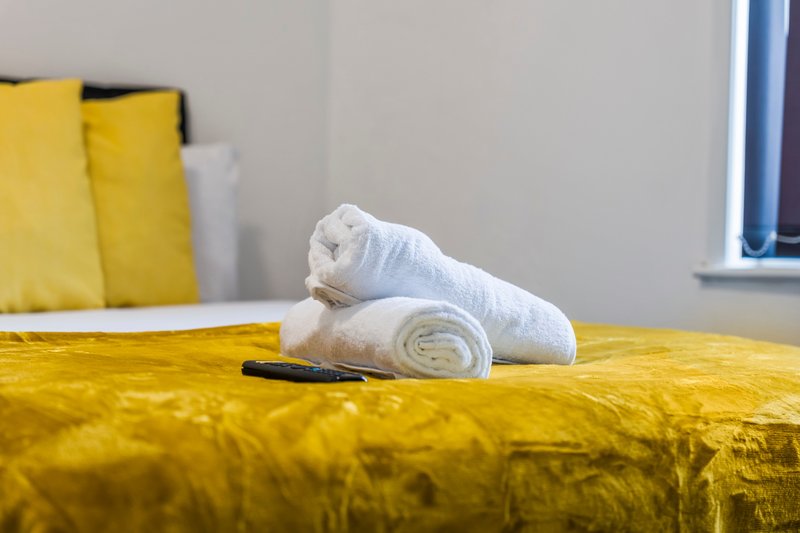 Yellow table with rolled white towel and dark object, bright interior space