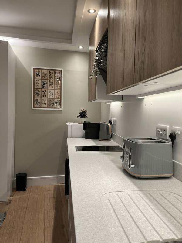 Modern galley kitchen with white countertop, stainless steel appliances and wooden cabinetry