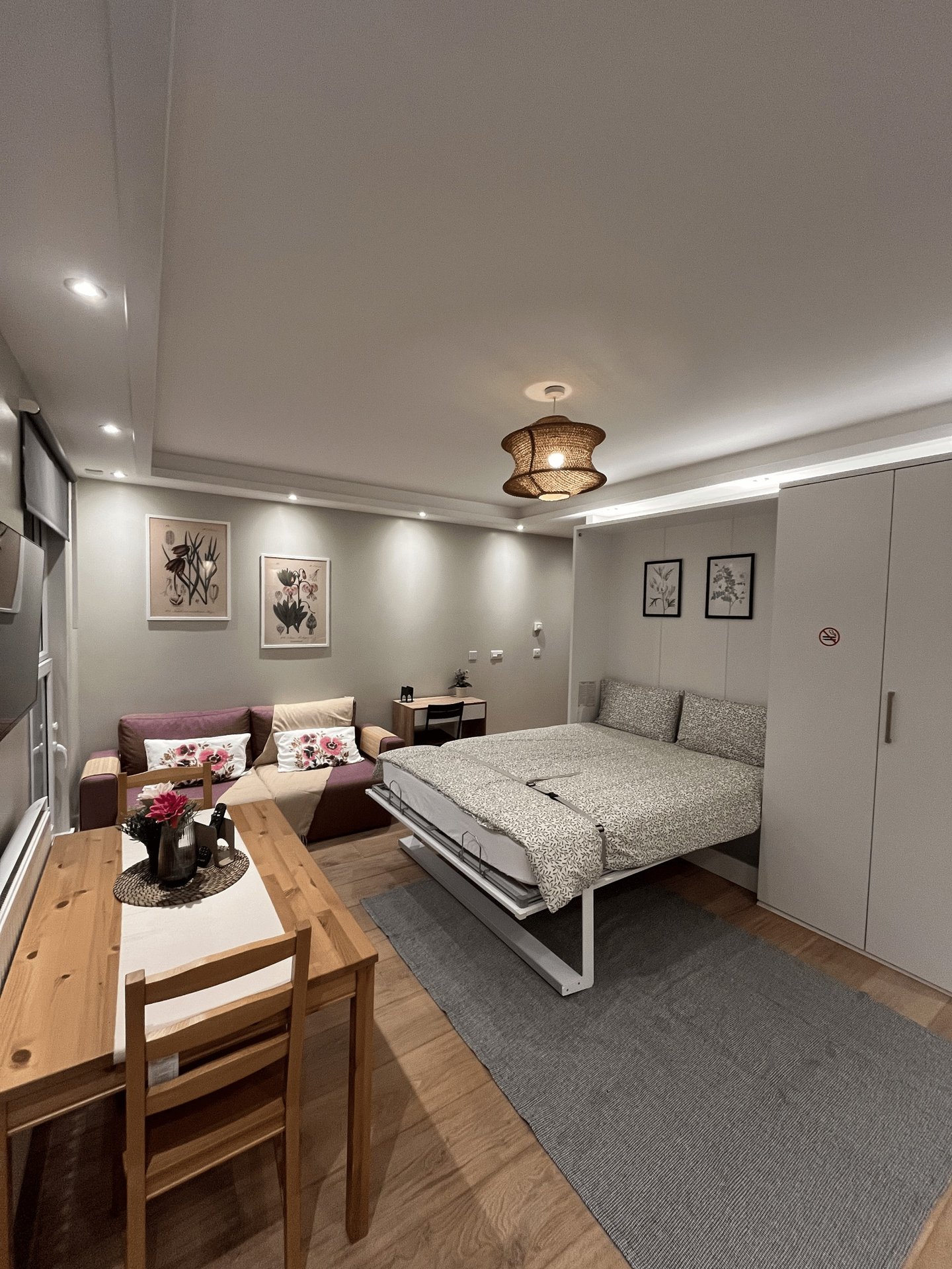 Studio apartment with bed, sofa, dining table, and kitchenette area