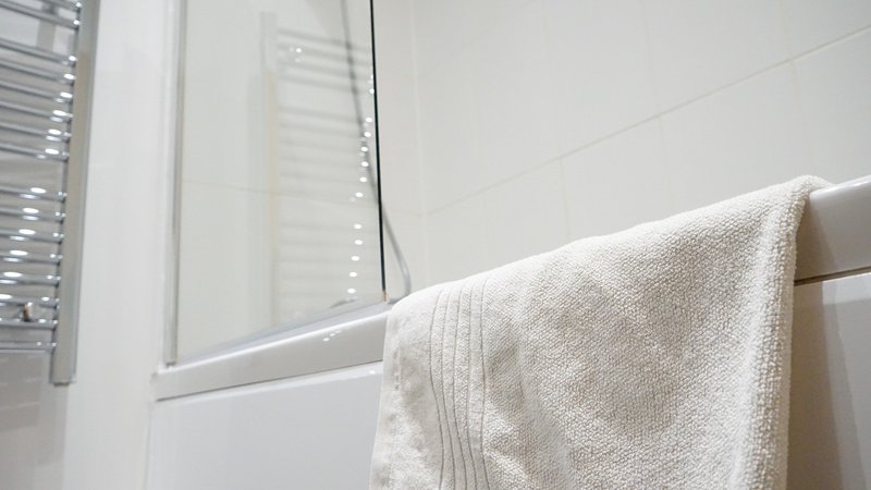 Modern bathroom with white window, towel rail and beige towel