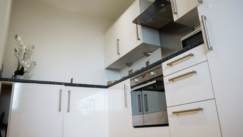 Modern kitchen with white cabinetry, stainless steel oven, and wooden handles