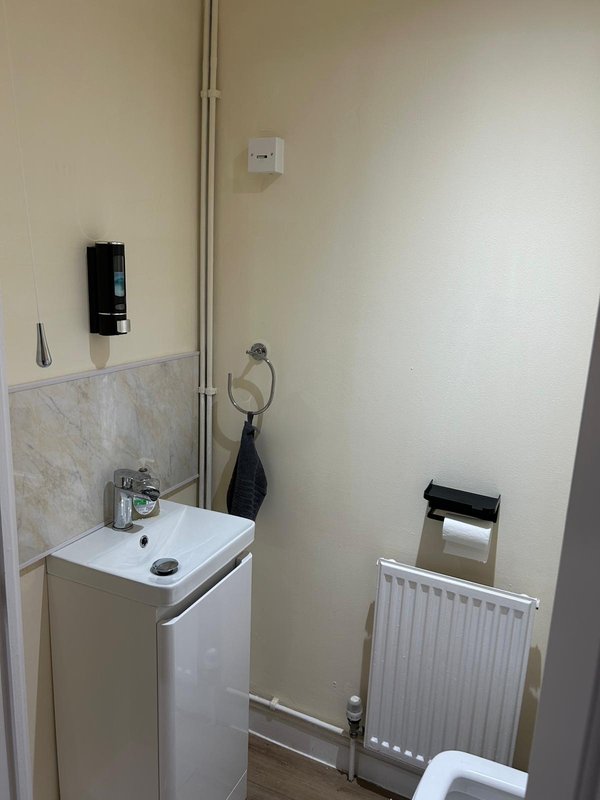 Compact bathroom with wall-mounted sink, radiator, soap dispenser and toilet