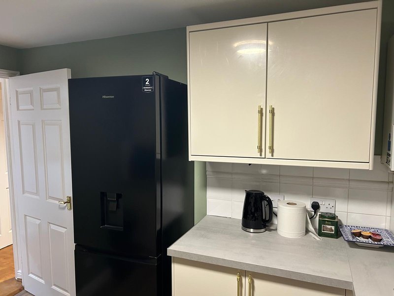 Kitchen with cream cabinets, black refrigerator, white subway tile backsplash and countertop appliances