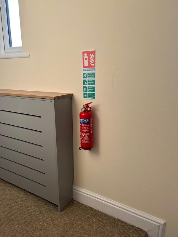 Beige wall with fire extinguisher and safety instruction signs mounted