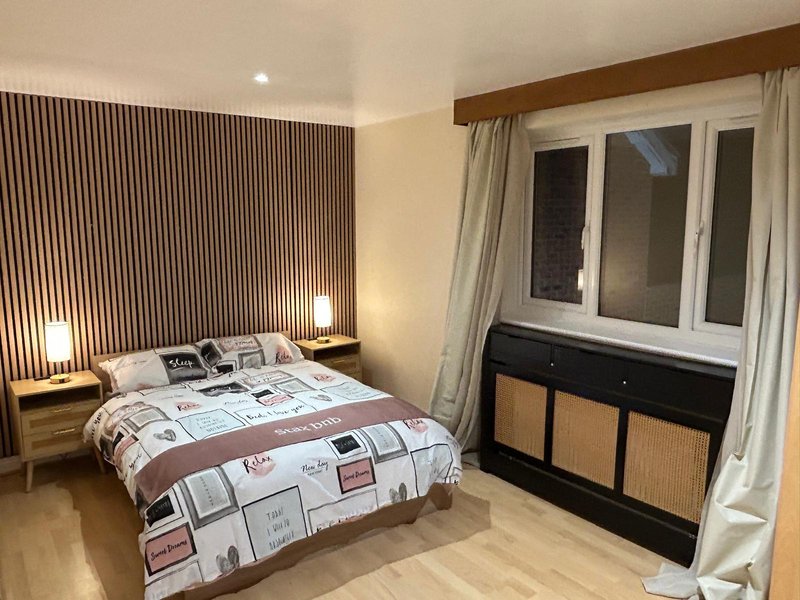 Modern bedroom with double bed, wooden bedside tables, accent wall paneling and large windows
