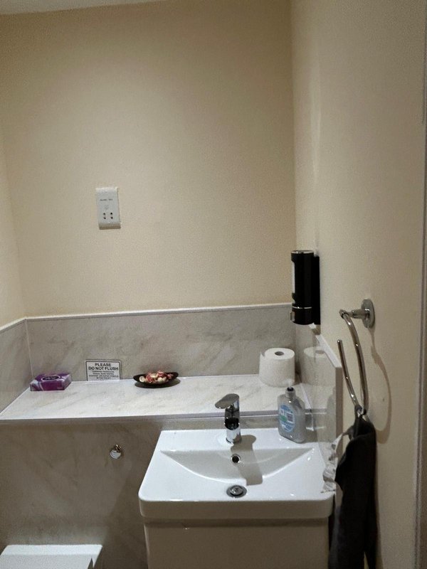 Bathroom with sink, mirror, toilet, and marble-tile backsplash