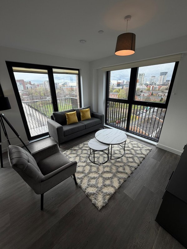 Modern living room with black furniture, patterned rug, pendant lamp and city views