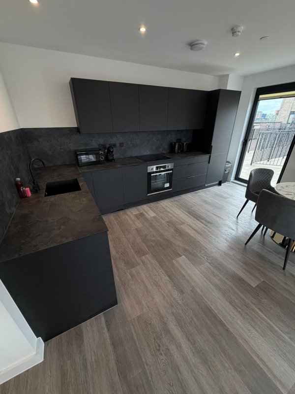 Modern open-plan kitchen with black cabinetry, island counter, and dining area