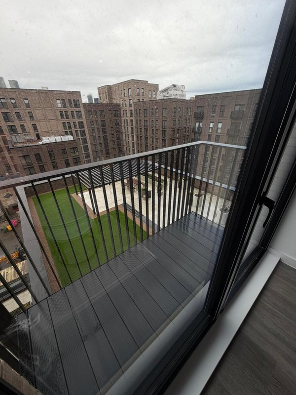 Balcony with metal railings overlooking urban courtyard and brick apartment buildings