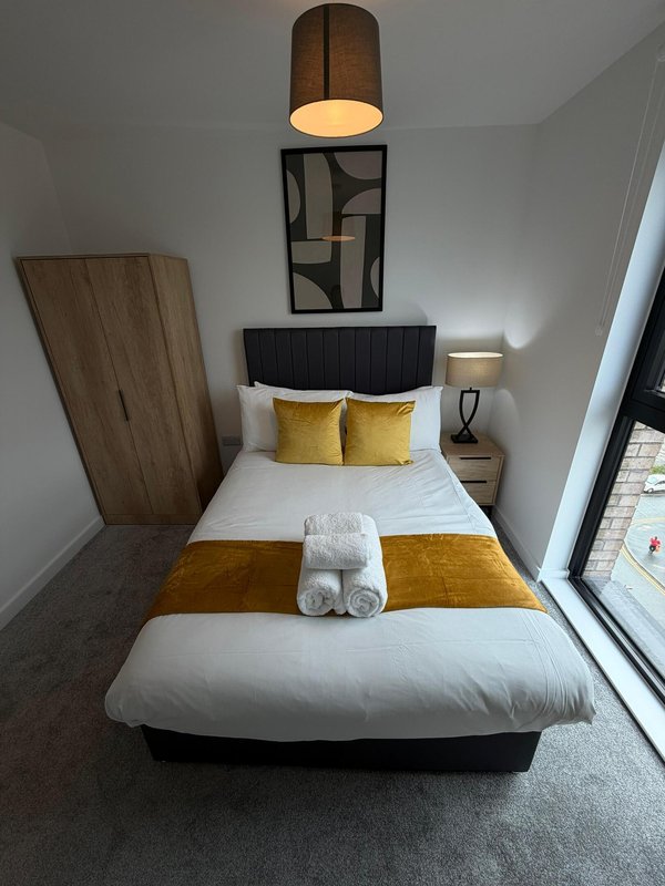 Modern bedroom with double bed, yellow cushions, pendant lamp and wall art