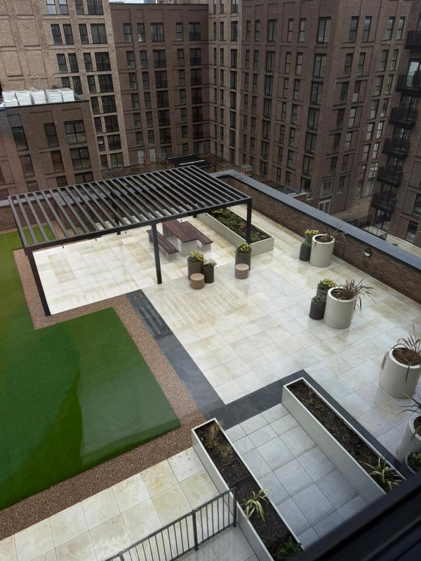 Rooftop terrace with paving, pergola, planters and surrounding urban buildings