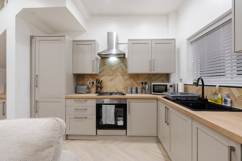 Modern kitchen with cream cabinets, wood countertops, black range cooker and herringbone backtile
