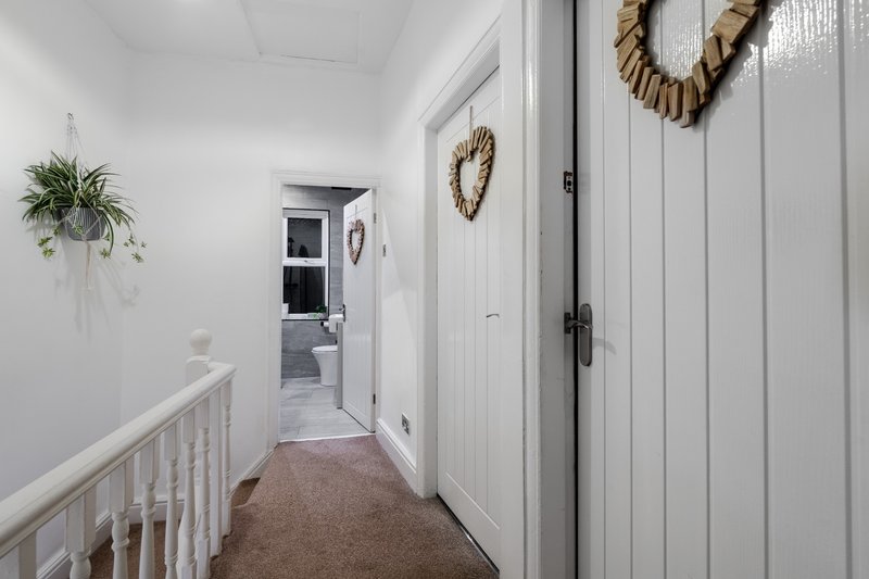 Hallway with white wooden door, hanging plant, and decorative heart wreath