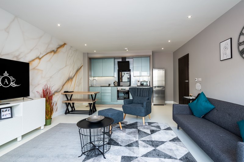 Open-plan living area with kitchen, dining table, sofa, TV and marble feature wall