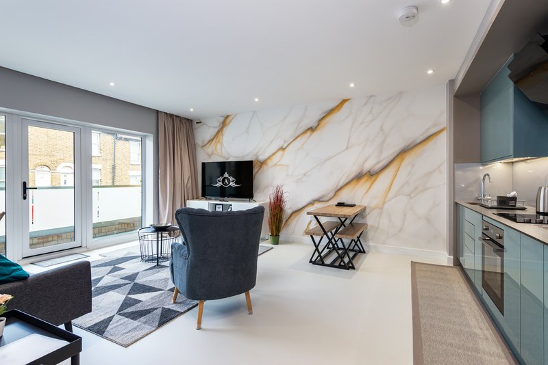 Modern open-plan living space with marble accent wall, kitchen, seating area and glass doors