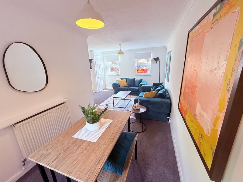 Open-plan living space with dining table, blue sofa, and abstract wall art