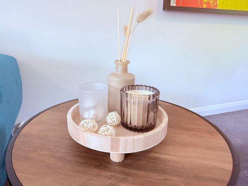 Wooden round table with decorative items including candles, reed diffuser and woven balls