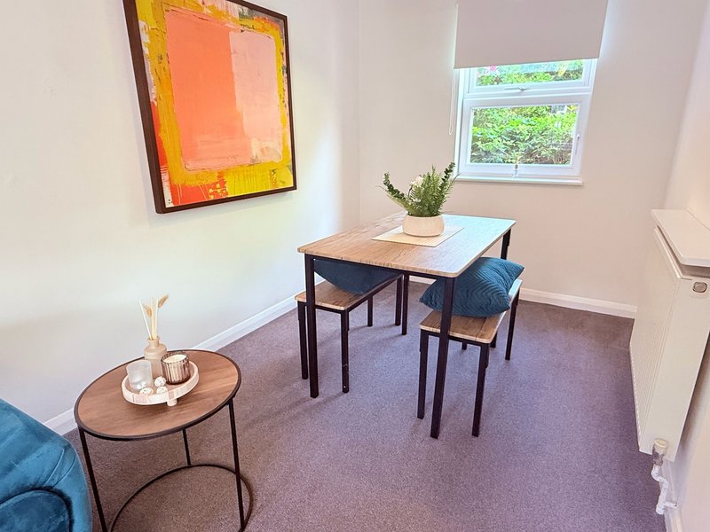Modern office space with desk, chairs, round side table and framed artwork on wall