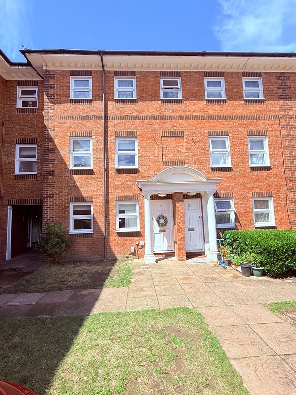 Red brick apartment building exterior with white entrance door and multiple windows