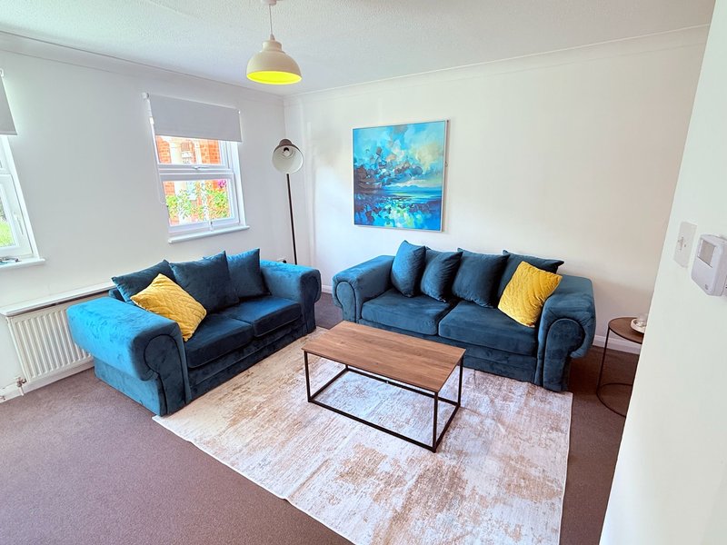 Bright living room with two blue sofas, wooden coffee table, yellow pendant light and blue artwork