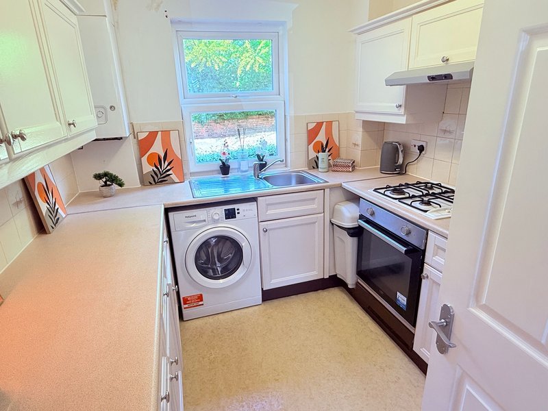 Modern kitchen with white cabinetry, washing machine, gas hob and oven, blue countertop