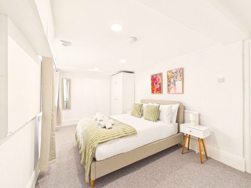 Modern bedroom with double bed, yellow bedding, white pillows, wooden nightstand and recessed ceiling lights