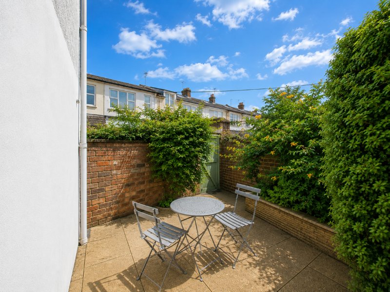 Courtyard patio with round table, folding chairs, brick walls and climbing ivy