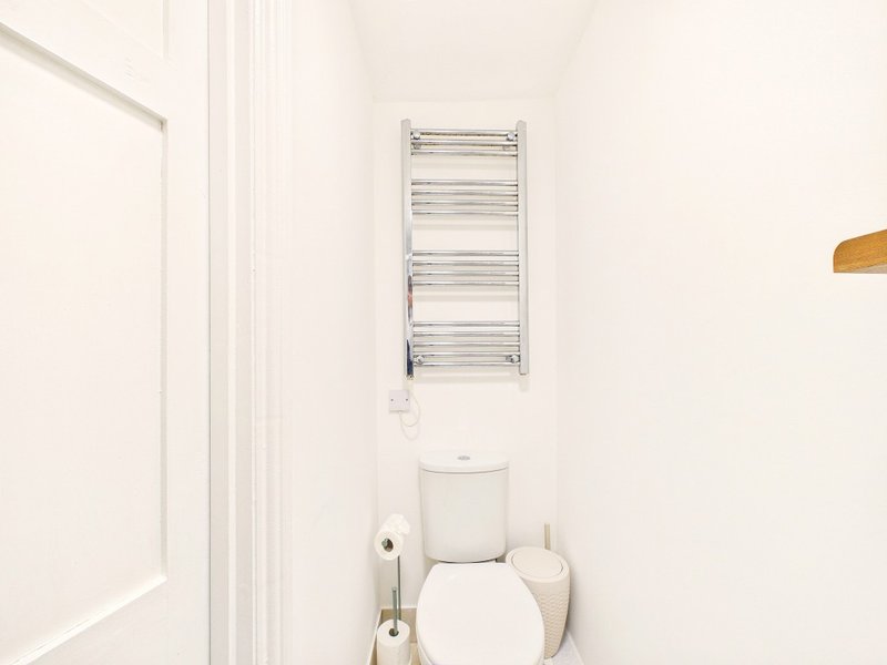 Small bathroom with white toilet, towel radiator and cream walls