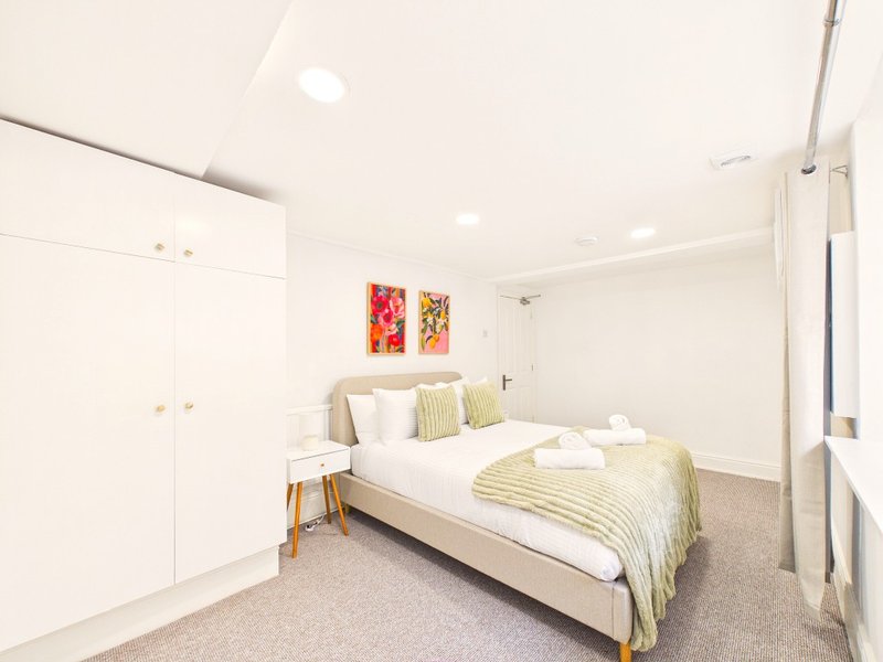 Modern bedroom with double bed, white built-in wardrobes, and colorful wall art