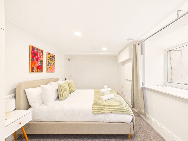 Bright bedroom with double bed, white pillows, colorful wall art and ensuite bathroom