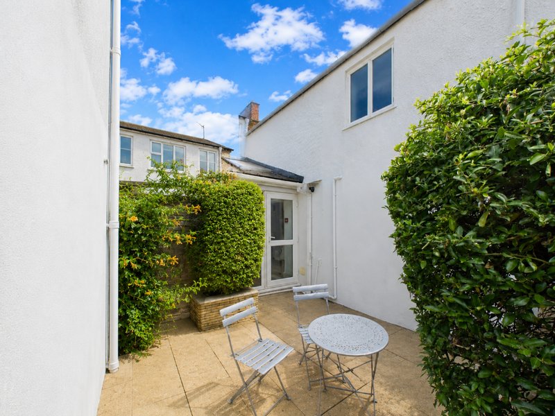 Paved courtyard with table, chairs, ivy-covered walls and white building exterior