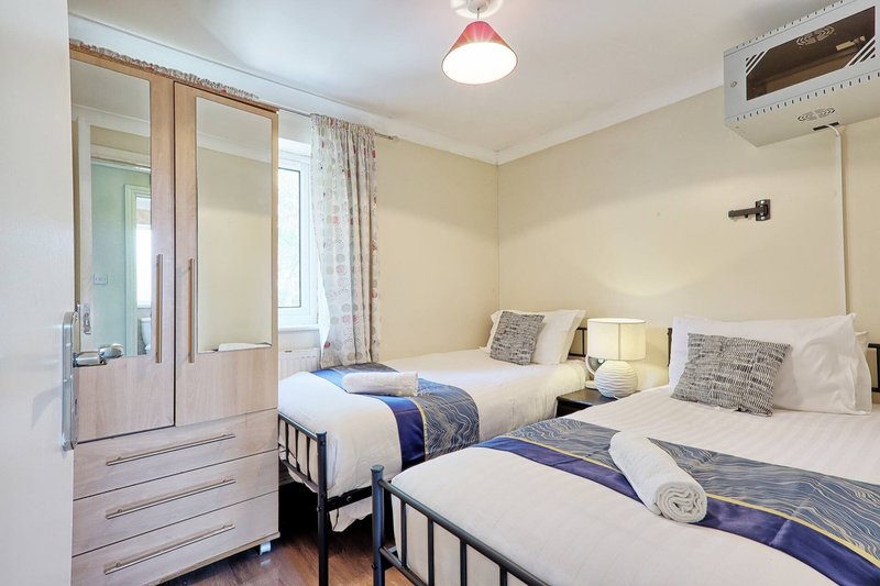 Twin bedroom with two single beds, wardrobe, window with curtains and ceiling light