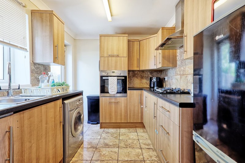Modern kitchen with wooden cabinets, black countertops, integrated appliances and tile flooring