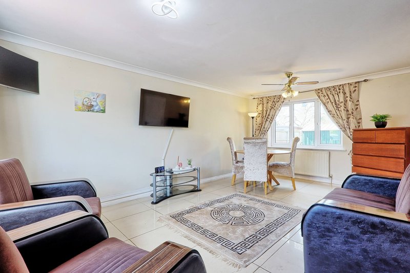 Bright living room with two upholstered chairs, TV, dining table, patterned rug and window
