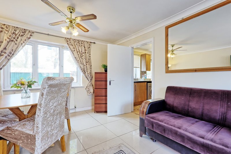 Open-plan living area with purple sofa, dining chair, ceiling fan and sea view from windows