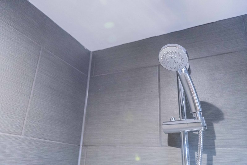 Modern bathroom shower head and chrome fixture against tiled wall