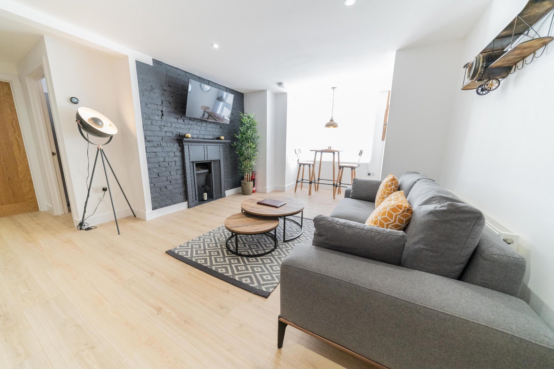 Modern open-plan living room with gray sofa, fireplace, wooden flooring and dining area
