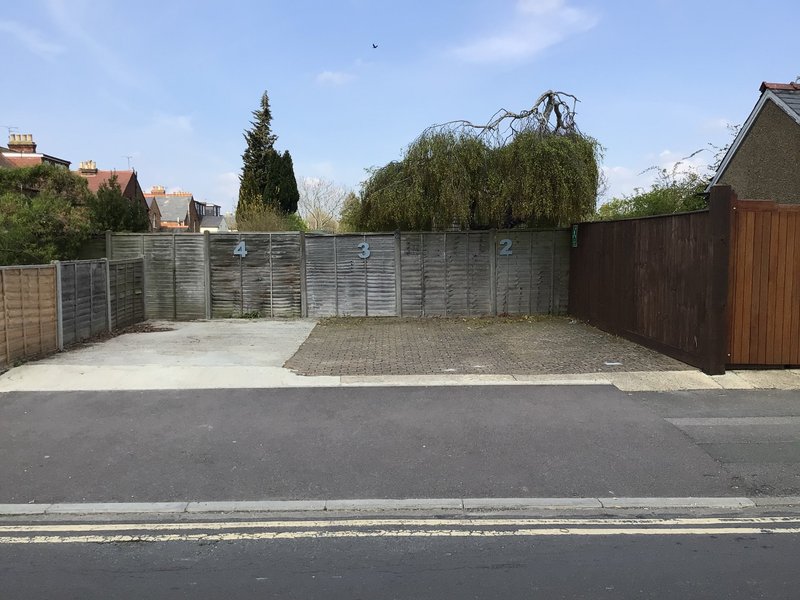 Driveway and parking area with grey fencing, gravel, and residential street view