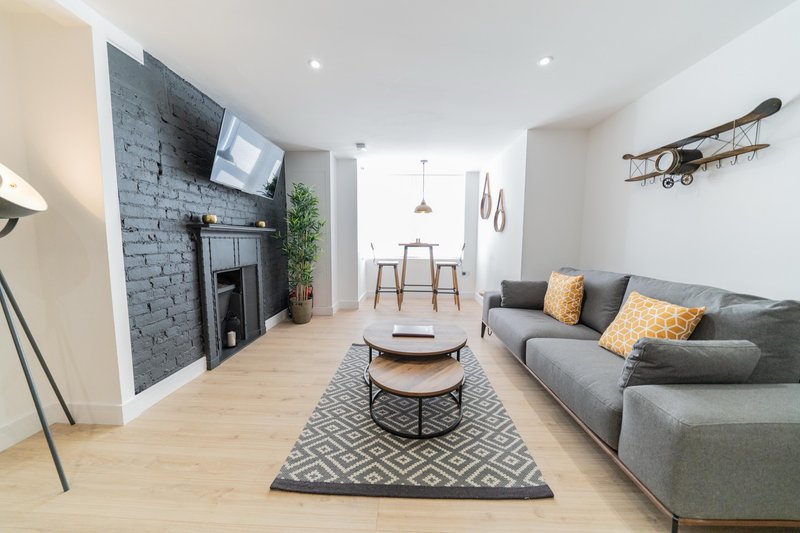 Open-plan living room with grey sofa, fireplace, wooden flooring and modern furnishings