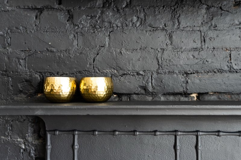 Dark brick wall with two gold-painted decorative lights on a shelf