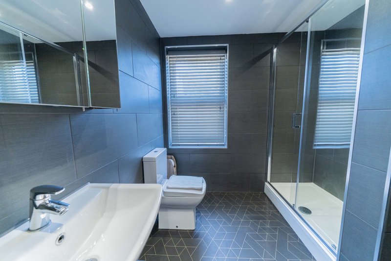 Modern bathroom with white sink, toilet, shower enclosure and blue tile walls