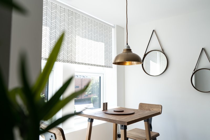 Bright workspace with wooden desk, pendant lamp, round mirrors, and potted plants by window