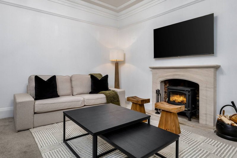 Modern living room with beige sofa, black coffee table, fireplace and wall-mounted TV