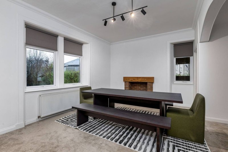 Bright dining room with black table, bench seating, striped rug and fireplace