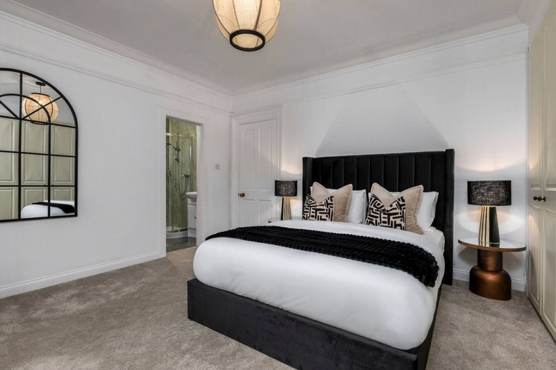 Modern bedroom with black upholstered bed, white bedding, decorative pillows and bronze table lamp