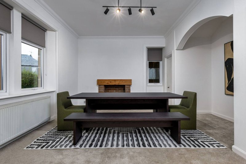 Modern dining room with black table, green chairs, striped rug and natural light