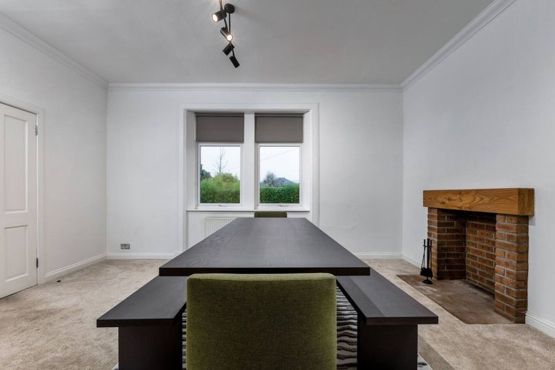 Modern dining room with black table, green chair, brick fireplace and large windows