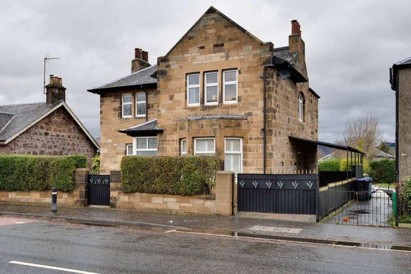 Stone-built Victorian house with black gates, driveway, and front hedges